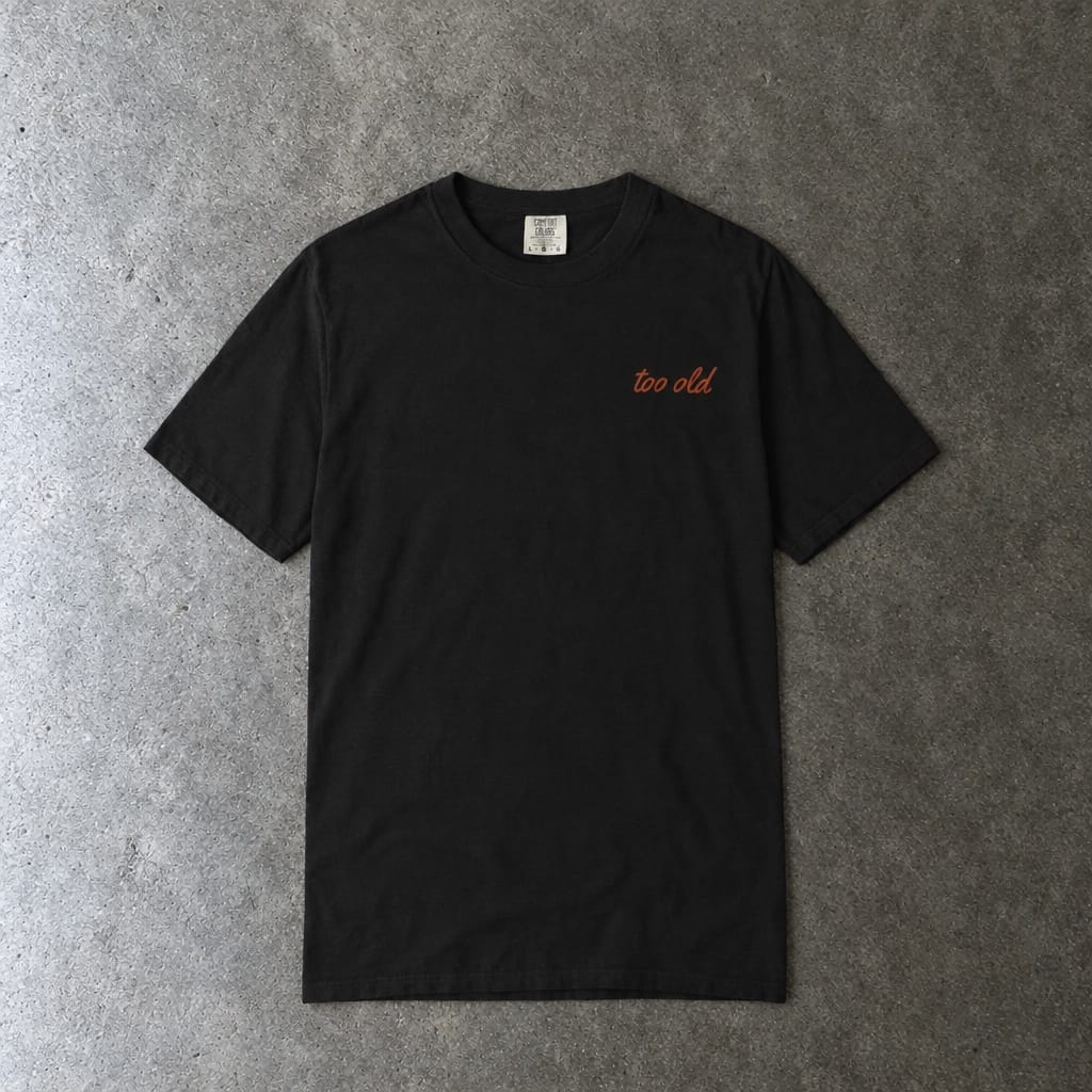 I'm Too Old For This Pit Danny Tee on Comfort Colors in black, laid flat